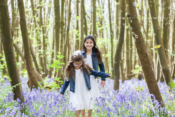 sister stepping carefully on a path through the bluebells at their kent bluebell photoshoot in sevenoaks