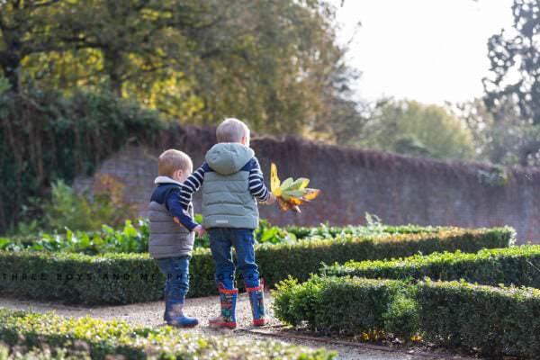 two boys holding autumn leaves wearing wellies at their autumn family photoshoot at Riverhill Himalayan Gardens Kent
