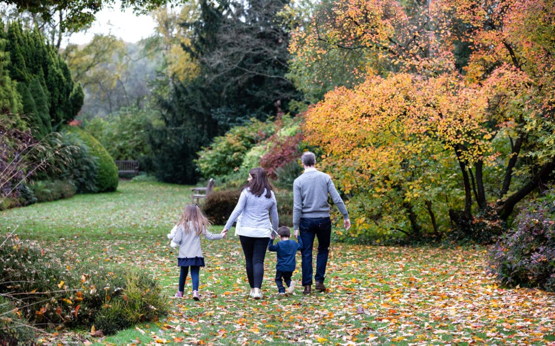family of four walking away holding hand at their autumn photoshoot at Great Comp Gardens in Sevenoaks