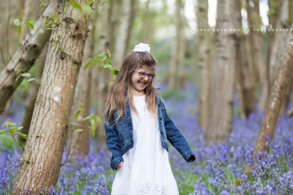 young girl in white dress dancing in the bluebells at Riverhill Gardens by Sevenoaks family photographer Nina Callow