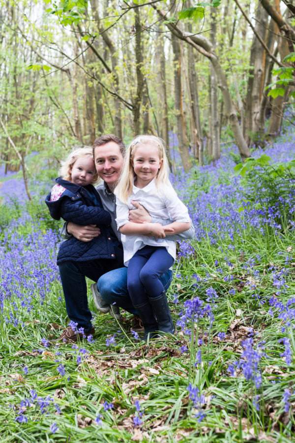 dad with his daughters sat in the bluebells at their Sevenoaks bluebell photoshoot