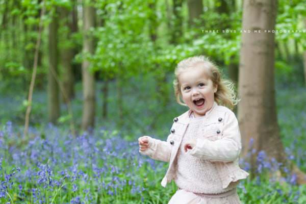 little girl wearing dusty pink laughing in the bluebells at her Bexley family photoshoot