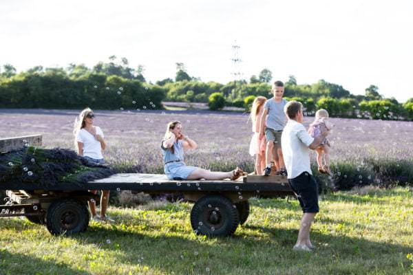 Children chasing bubbles sat on a tractor trailer at their kent lavender family photoshoot in Shoreham Kent