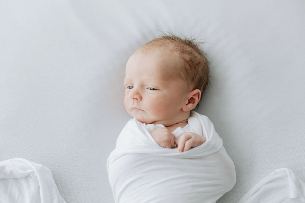 newborn baby wrapped in a white wrap on a white background at a Bexley newborn photoshoot