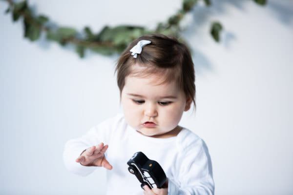 baby girl playing with wooden black taxi at her christmas photoshoot in Bexley