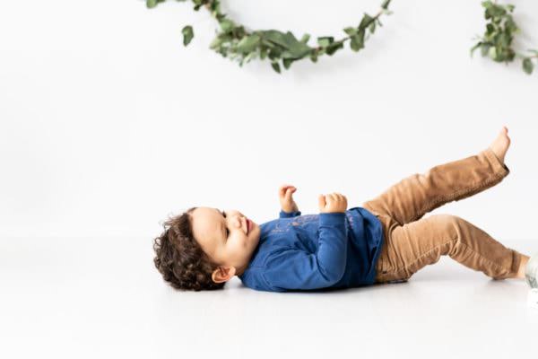 Baby boy laying on the floor smiling at his Christmas photoshoot in Bexley