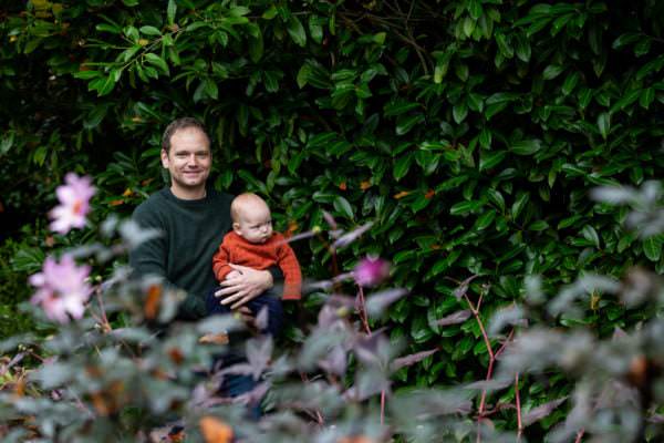 daddy with his new baby in amoungst laurel trees at his sevenoaks family photoshoot