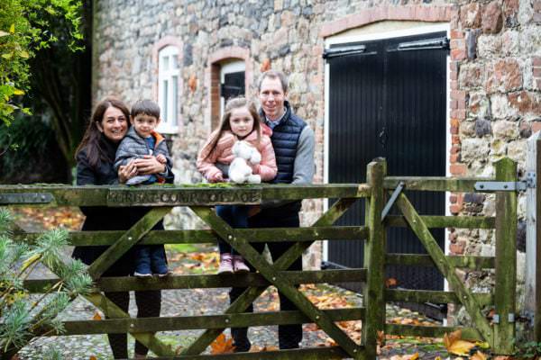 family standing by rustic old wooden gate at great comp gardens at their sevenoaks autumn photoshoot