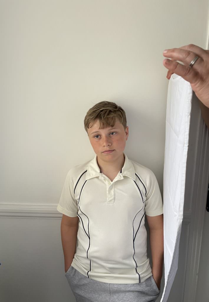 young child stands by wall demonstrating how use of white pillowcase eliminates shadows on face