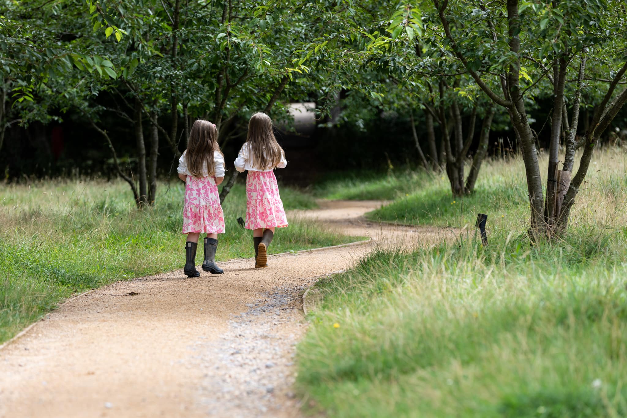 two sisters walk away from the camera in woodland at their sevenoask family photoshoot