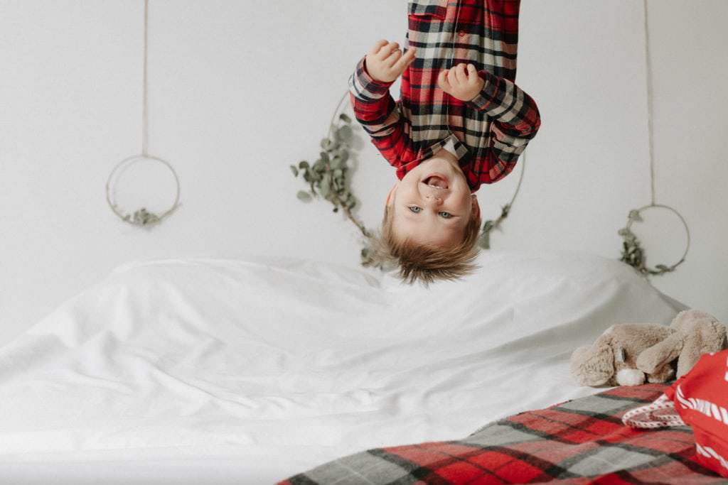 little boy upside down on a bed at his christmas mini shoot in bexley