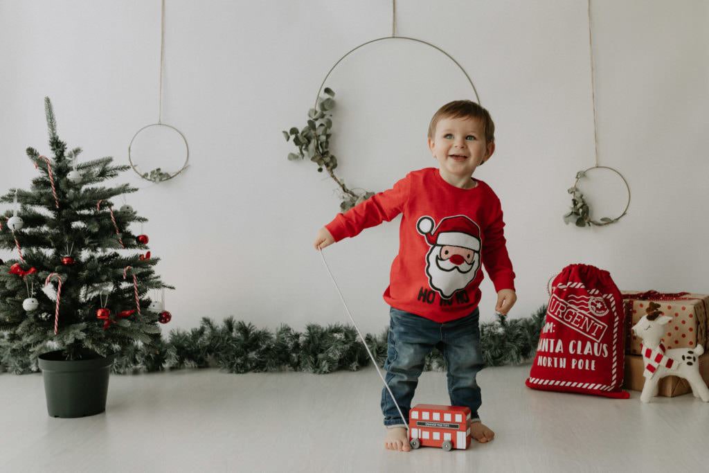 Little boy with pull a long red bus at his Kent Christmas photoshoot in Bexley