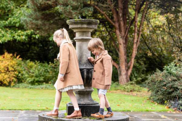 brother and sister walking round the sundial at great comp gardens at their family photoshoot in sevenoaks
