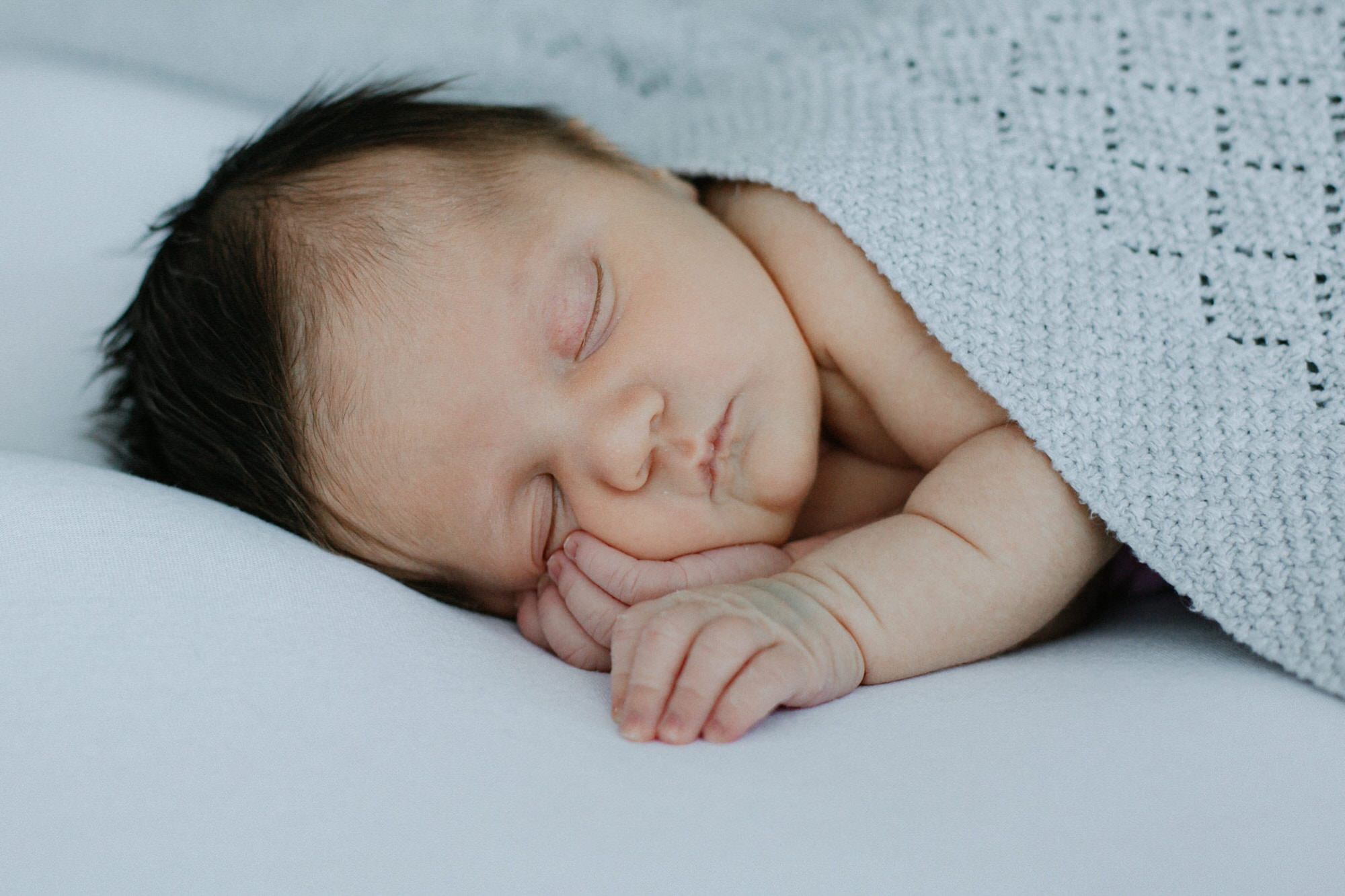 close up shot of newborn baby in white company blanket at her Bexley newborn photoshoot