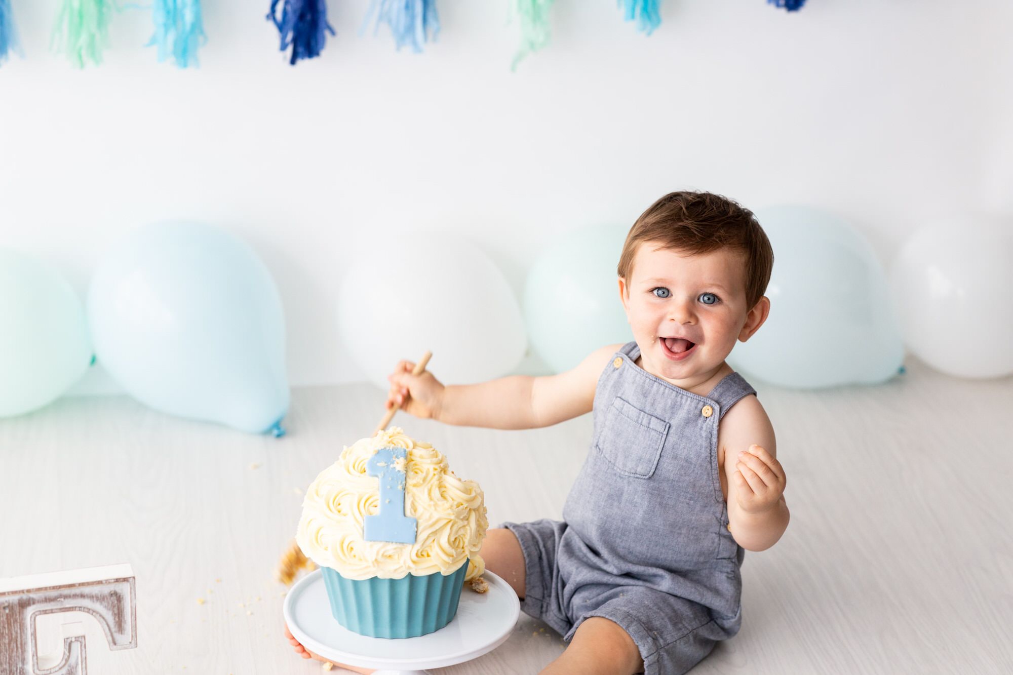 little boy in blue dungarees at his Bexley cake smash photoshoot