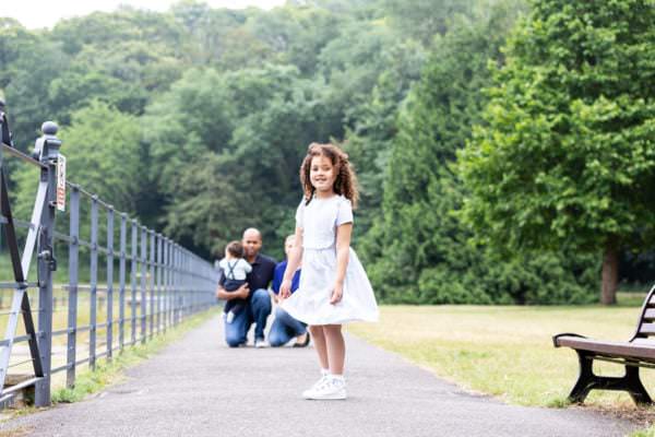 little girl looking ahead with mummy, daddy and baby brother behind out of focus, at their kent family photoshoot in bexley