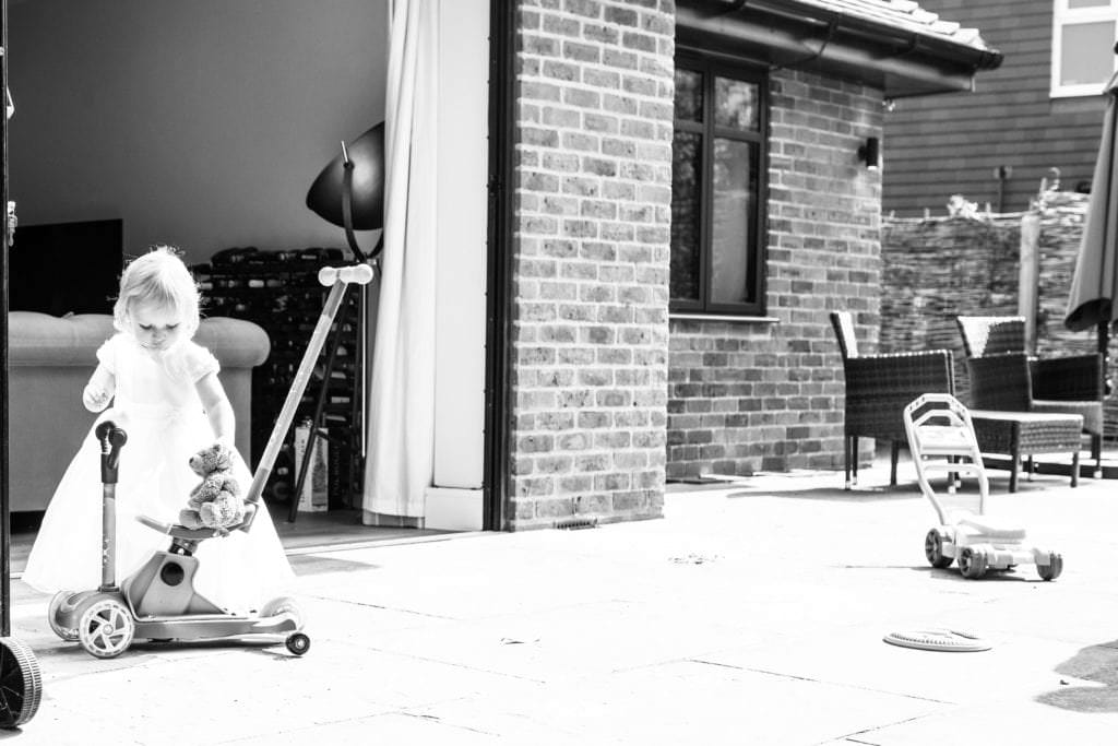 baby girl playing with her teddy on a scooter taken during a christening afterparty by kent christening photographer nina callow 3B&ME Photography Kent