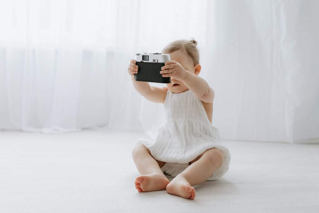 baby girl taking a selfie with a vintage camera at her Kent baby photoshoot in Bexley