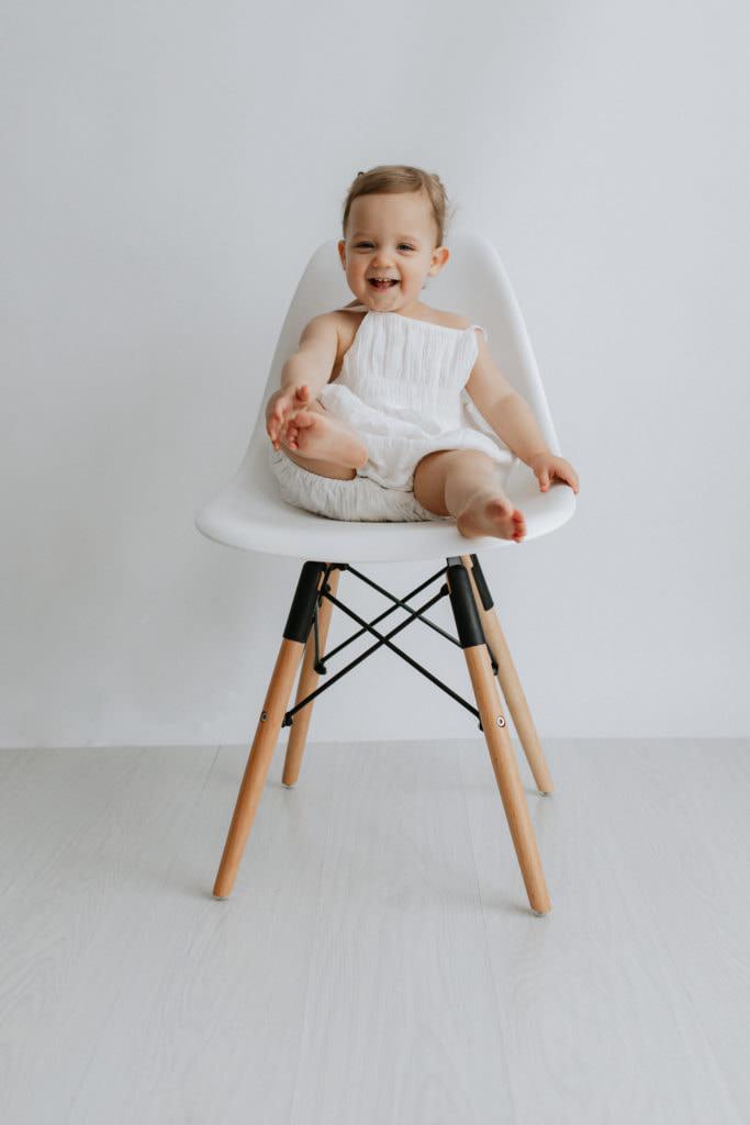 Baby girl sat on a white Eames style chair at her Kent photoshoot in Bexley