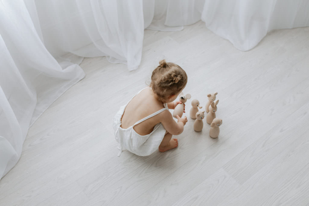 shot from above of little girl playing with wooden skittles at her Kent baby photoshoot in Bexley