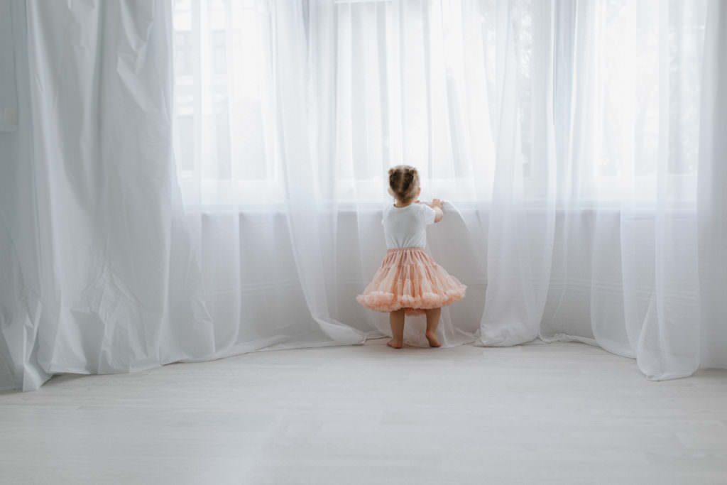 baby girl standing at the window in a pink tutu looking out at her Kent baby photoshoot in Bexley