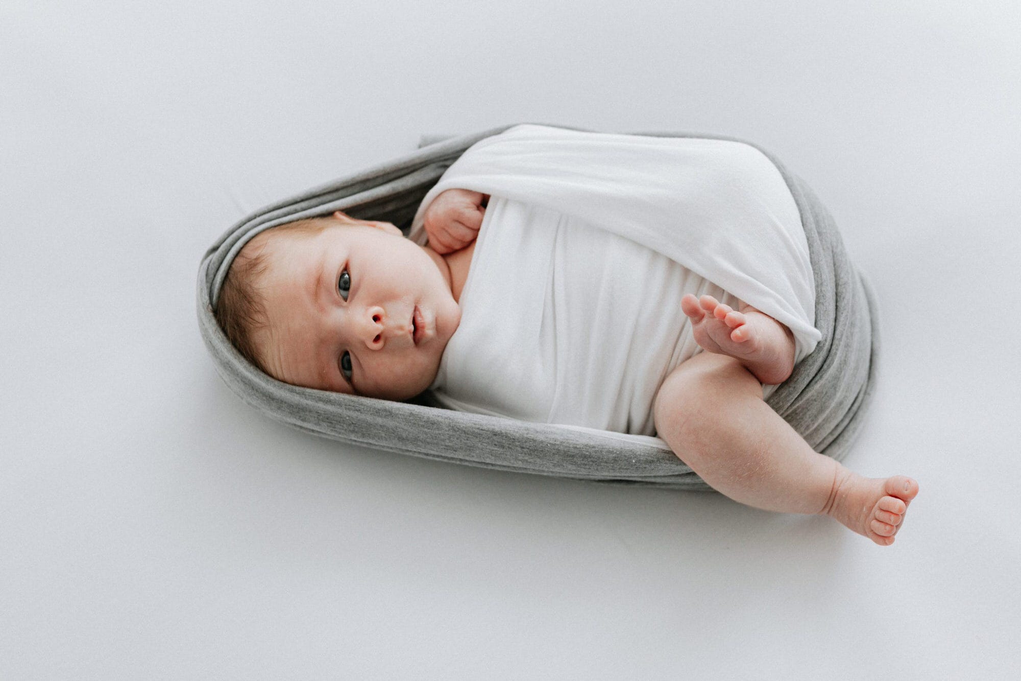 beautiful simple images of a newborn baby wrapped in white and grey at her kent newborn shoot in bexley