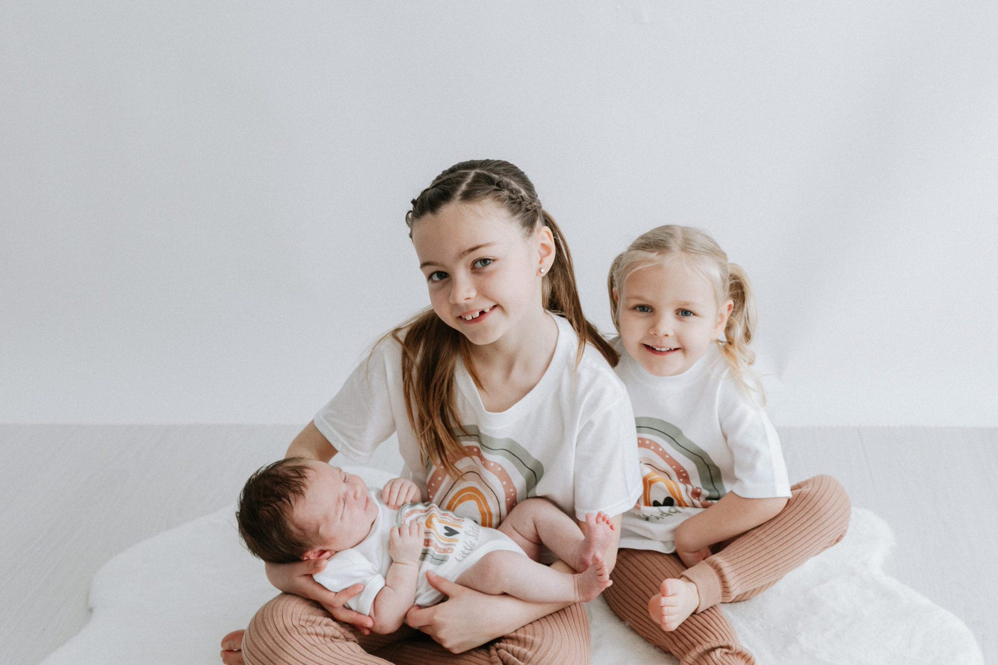3 sisters wearing cute rainbow tshirts at their kent newborn photoshoot in bexley