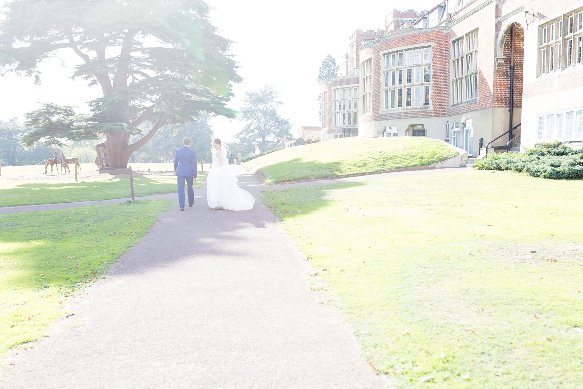 bride and groom walking into the sunlight at Selsdon Estate Weddings
