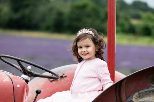 Little girl in a tiara and tutu sat on a vintage tractor at her Kent Lavender photoshoot in shoreham