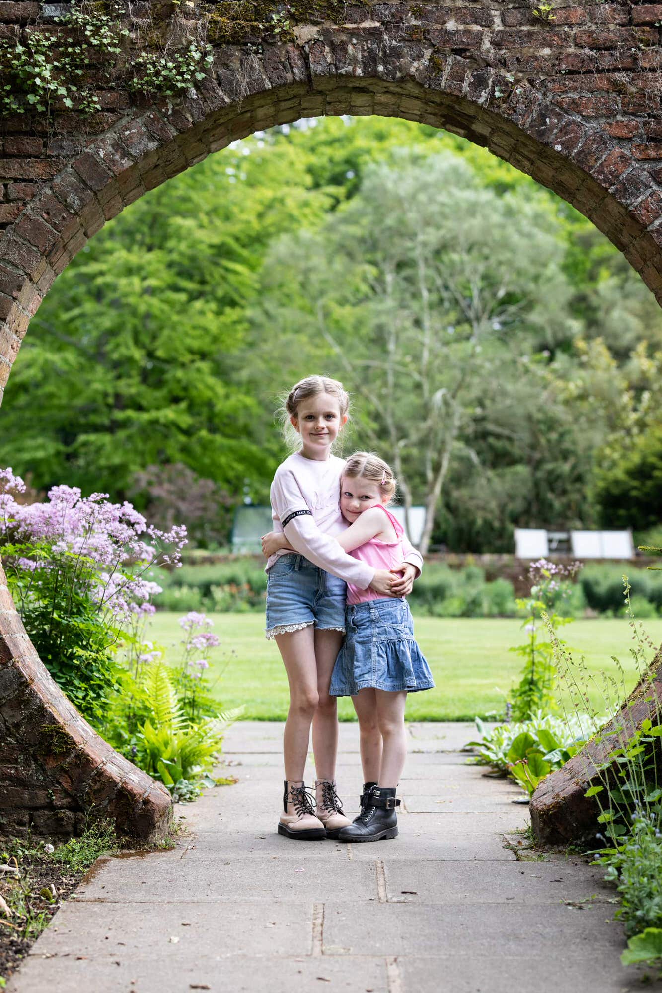 sisters stood in the iconic archway at Great Comp Gardens sevenoaks at their Kent family photoshoot