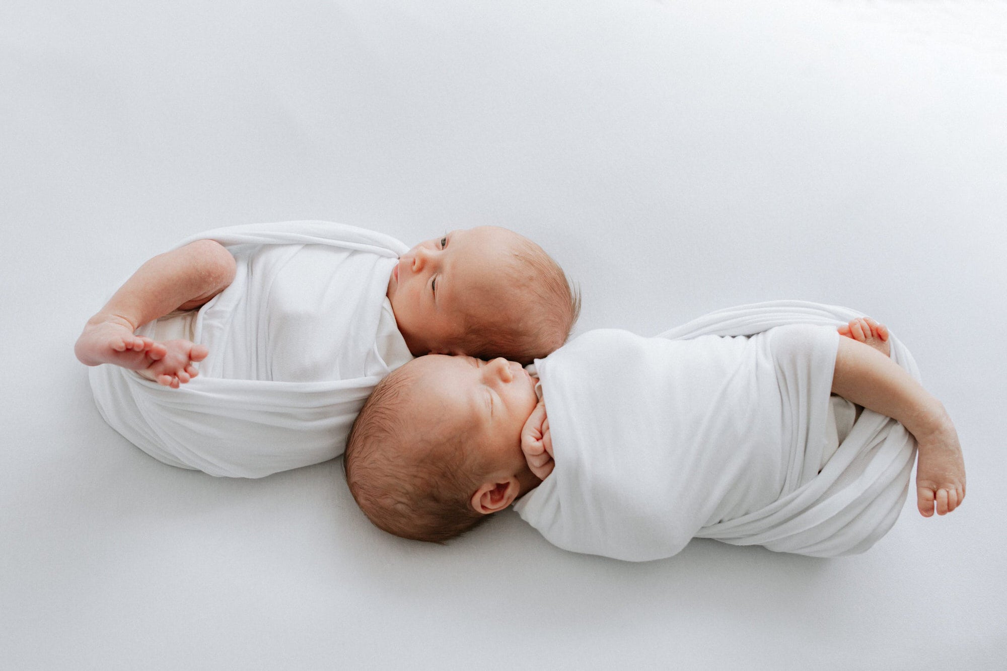 newborn twins image babies wrapped in white at their Kent newborn photoshoot in Bexley