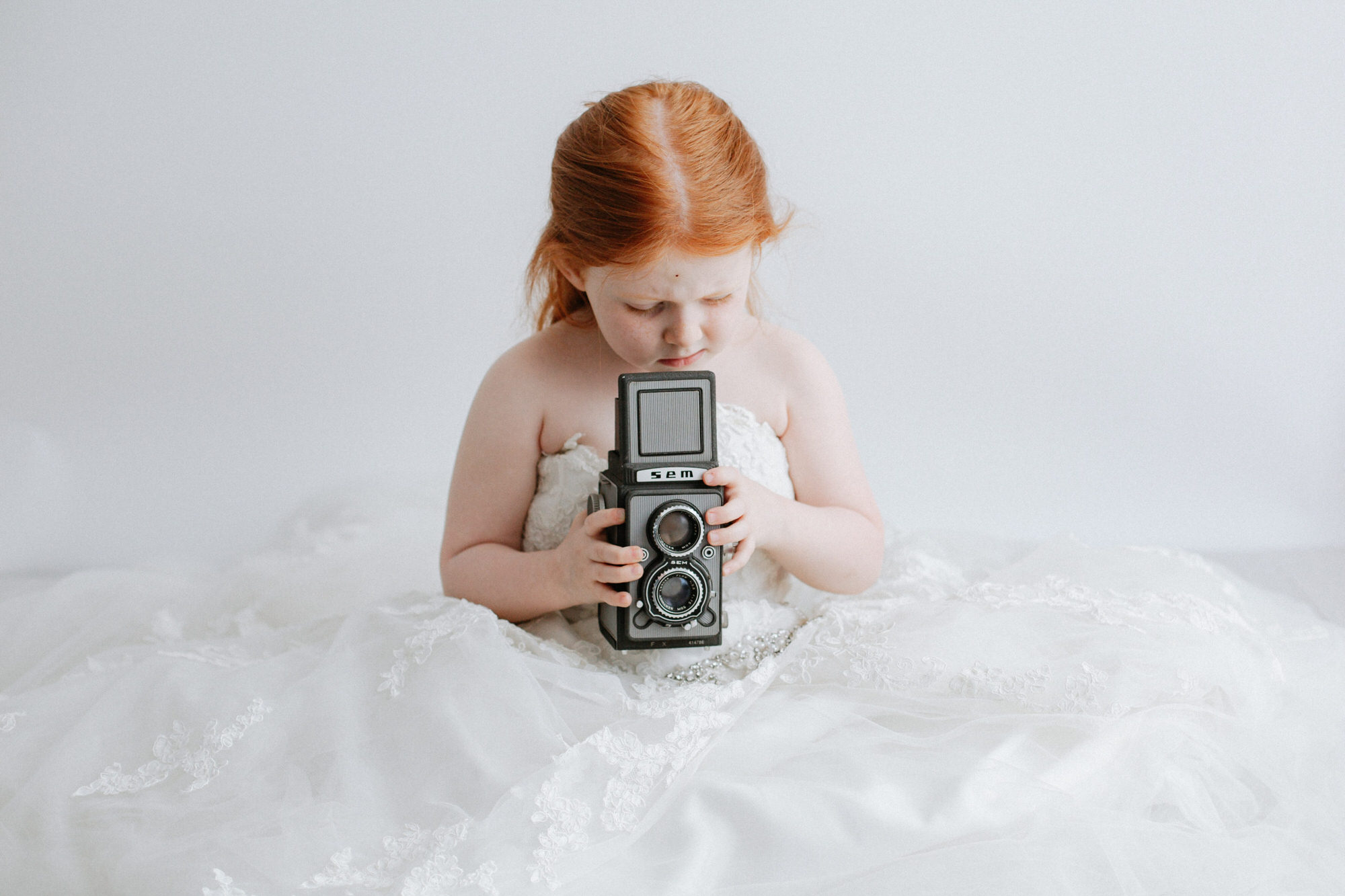 little girl at her Kent in mummy's wedding dress shoot holding a vintage camera