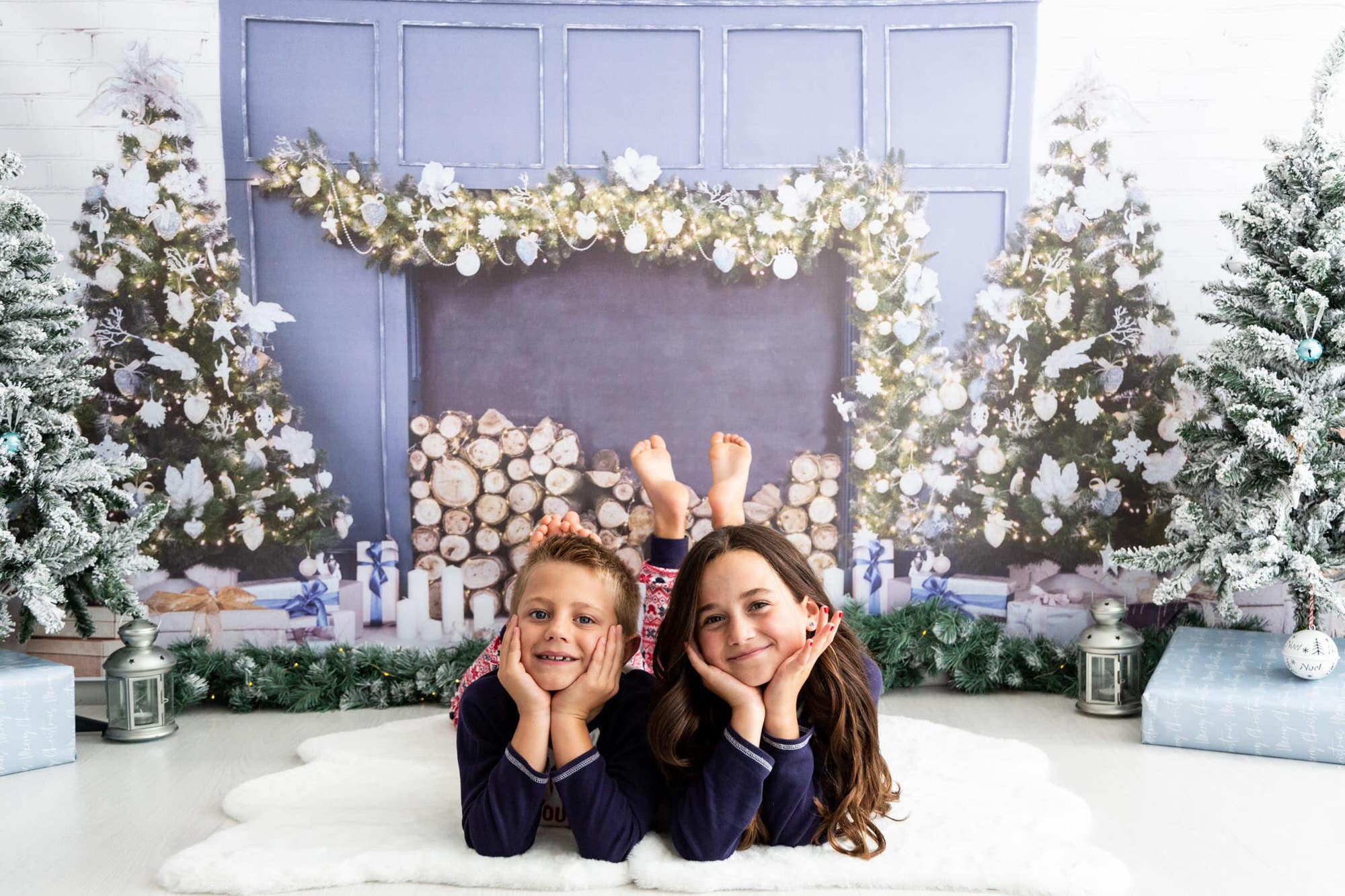 brother and sister in Christmas pyjamas in front of a Christmas fireplace at their Kent Christmas photoshoot in Bexley