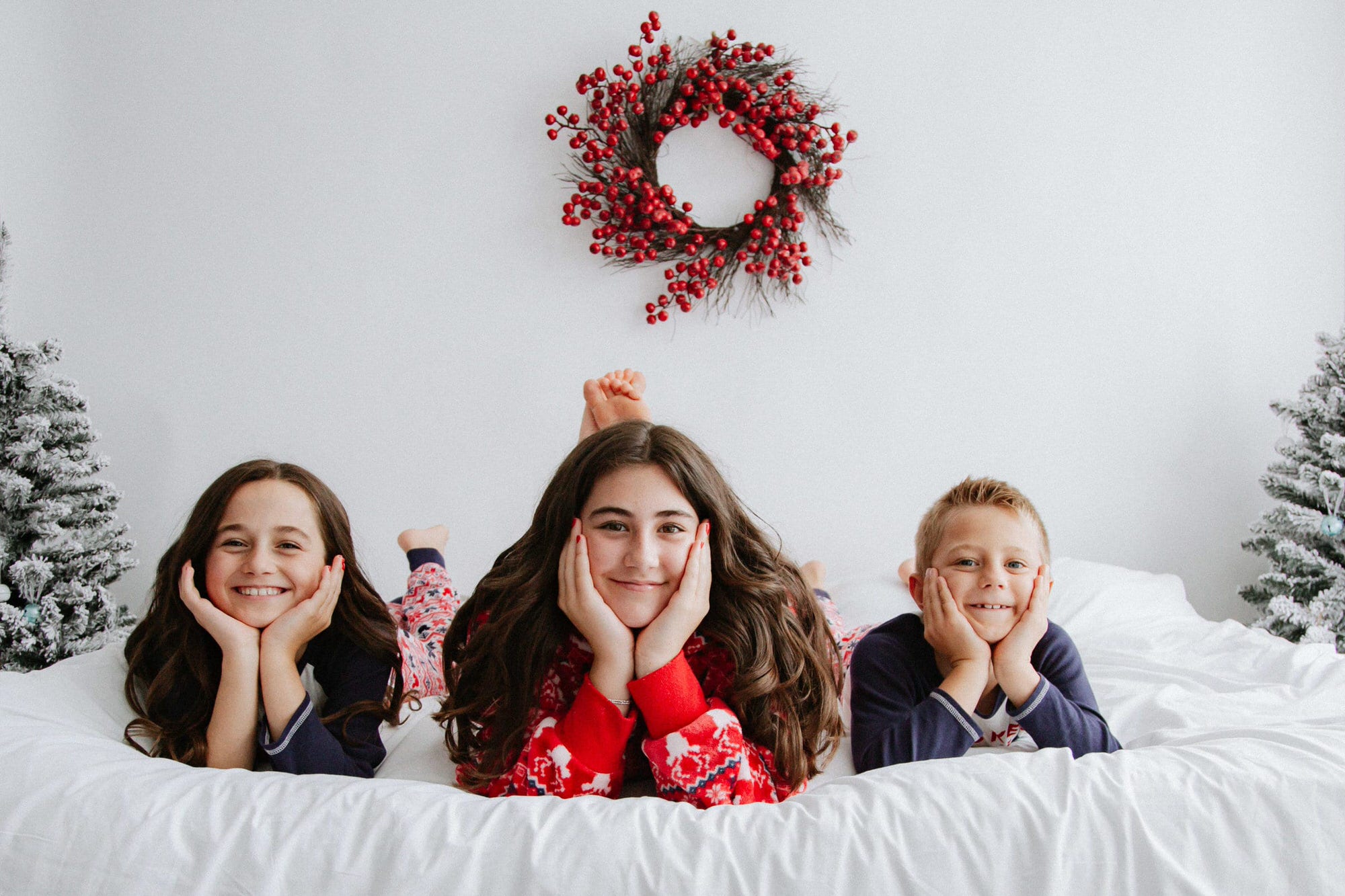 siblings laid on a white bed in a Christmas set at their Kent Christmas photoshoot in Bexley