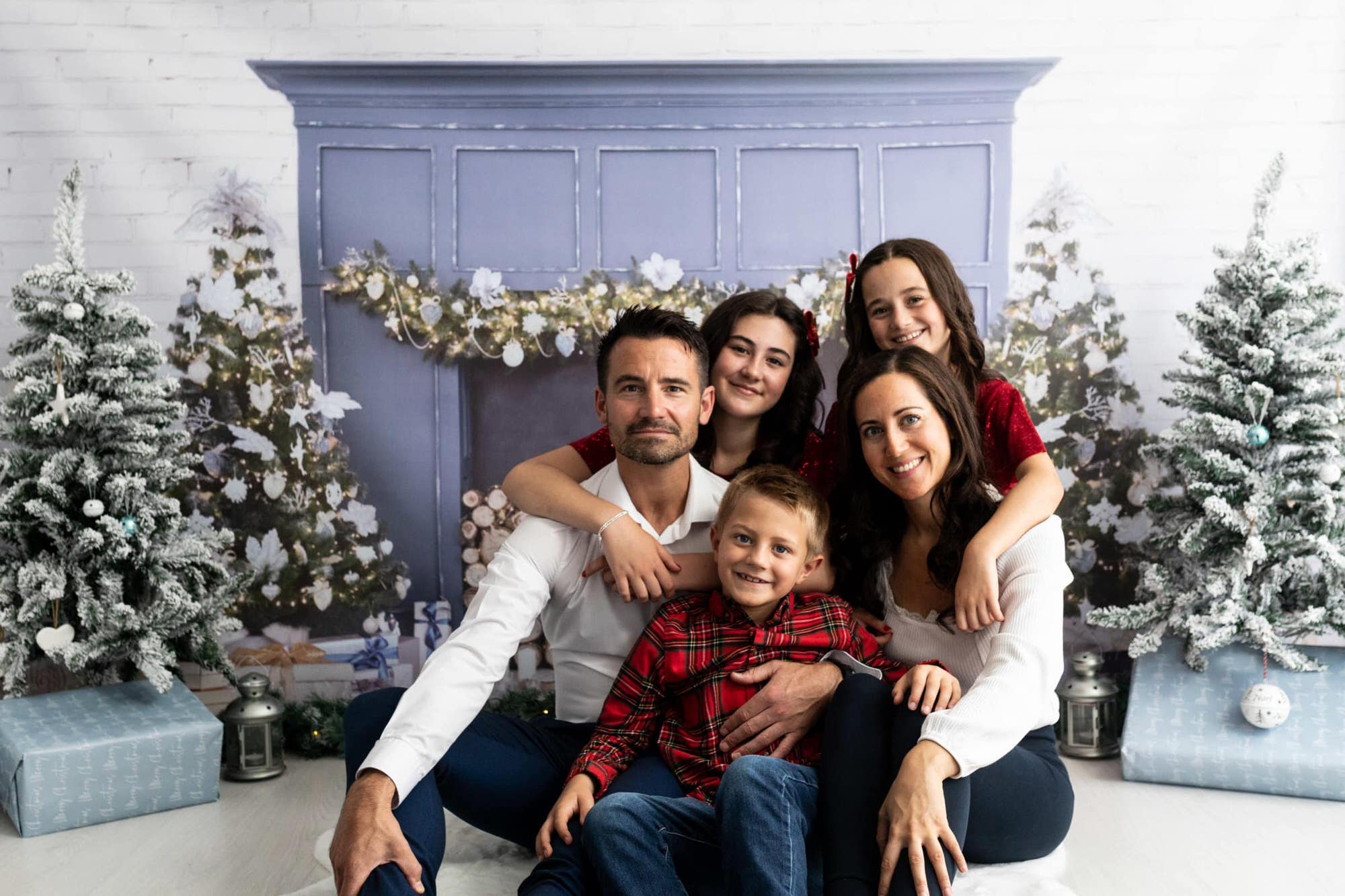family sat in front of a blue Christmas fire place at their Christmas photoshoot in Bexley