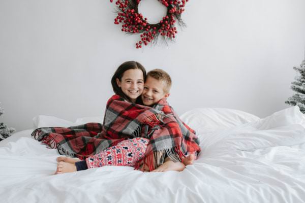 brother and sister wrapped in a tartan blanket at their Kent Christmas photoshoot in Bexley