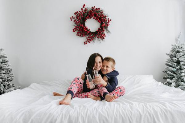brother and sister in Christmas pyjamas on a big white bed at their Kent Christmas photoshoot in Bexley