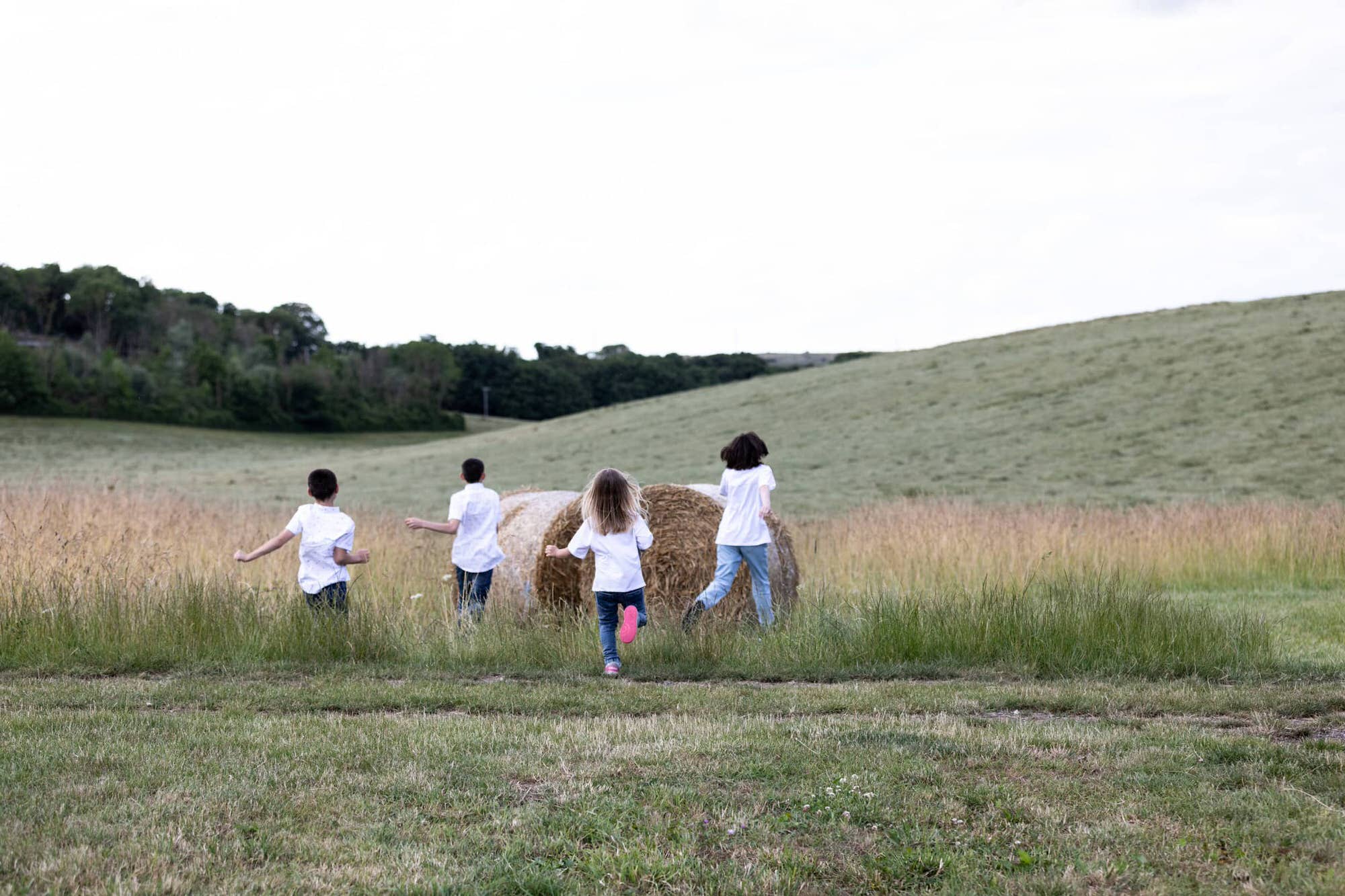 4 children running towards hay bales at their sevenoaks family photoshoot in Shoreham Kent