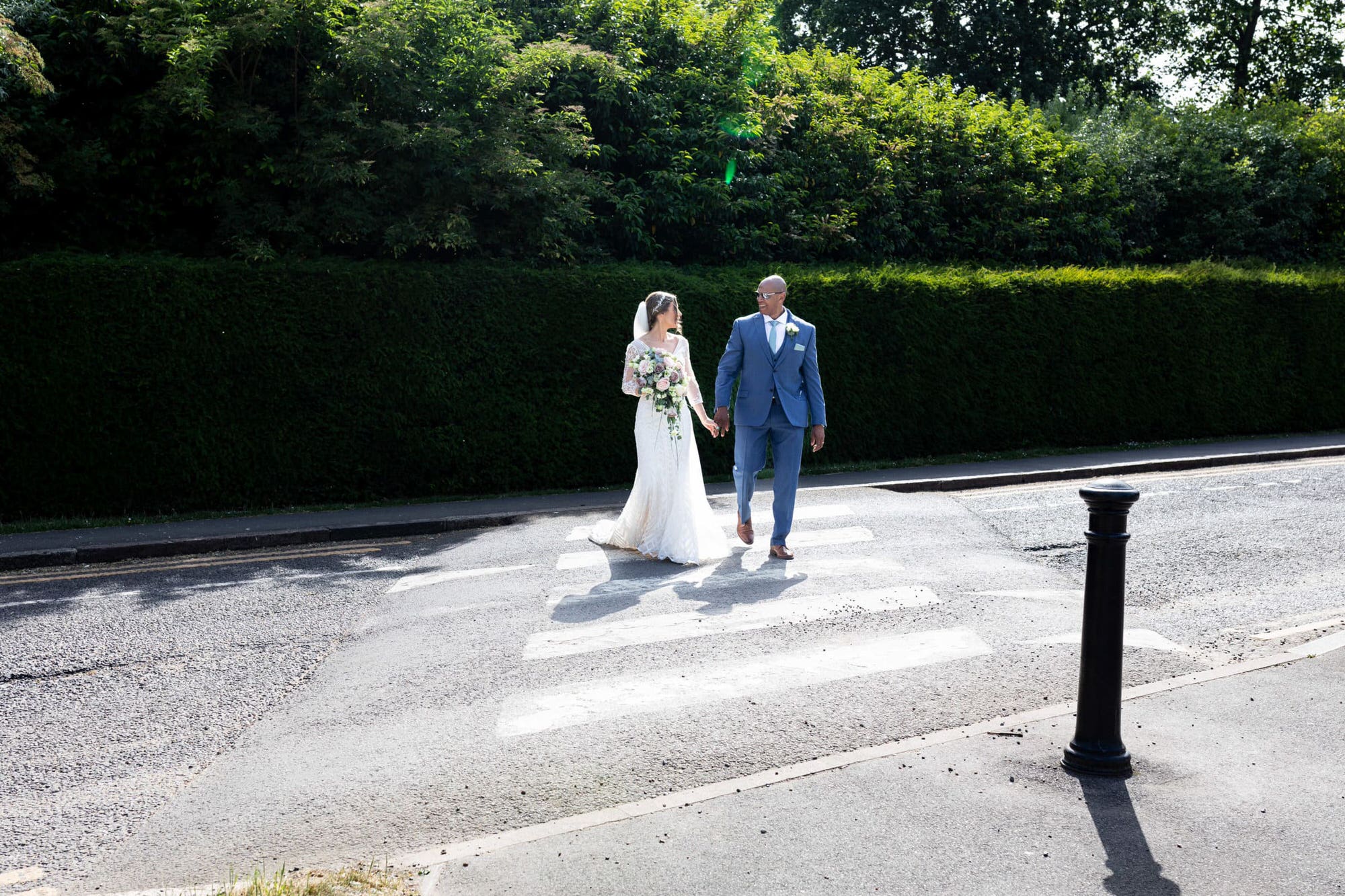 Bride and groom holding hands crossing at the zebra crossing at Danson House Bexleyheath wedding