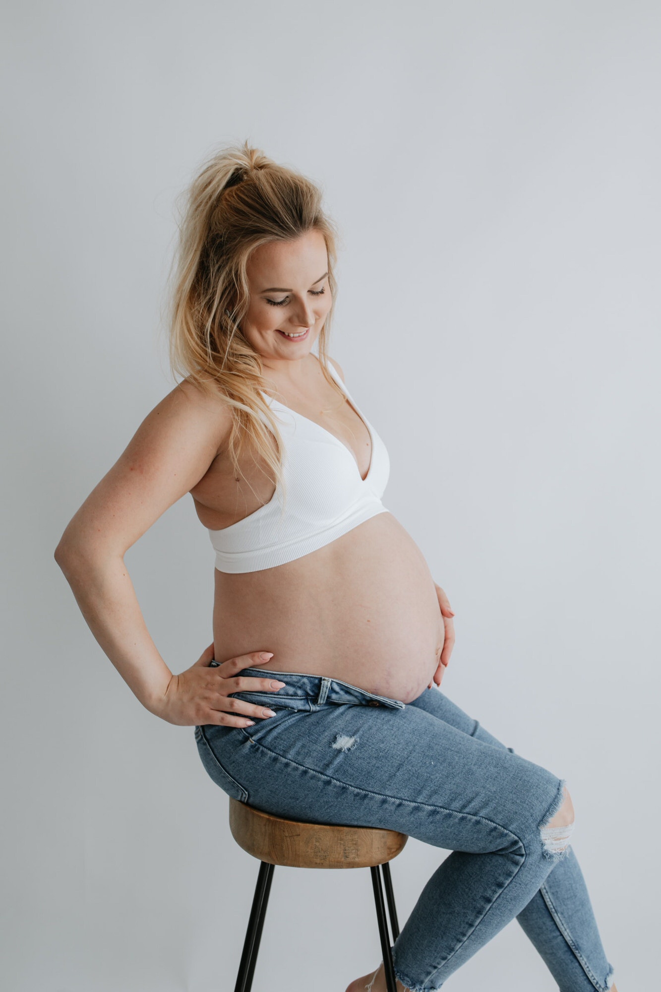 beautiful expectant mother in jeans holding her baby bump at her Kent maternity photoshoot in Bexley