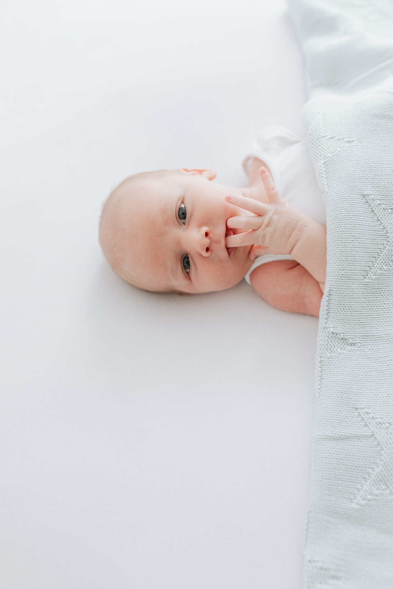 newborn baby boy with mint green blanket at his Kent newborn photoshoot in Bexley