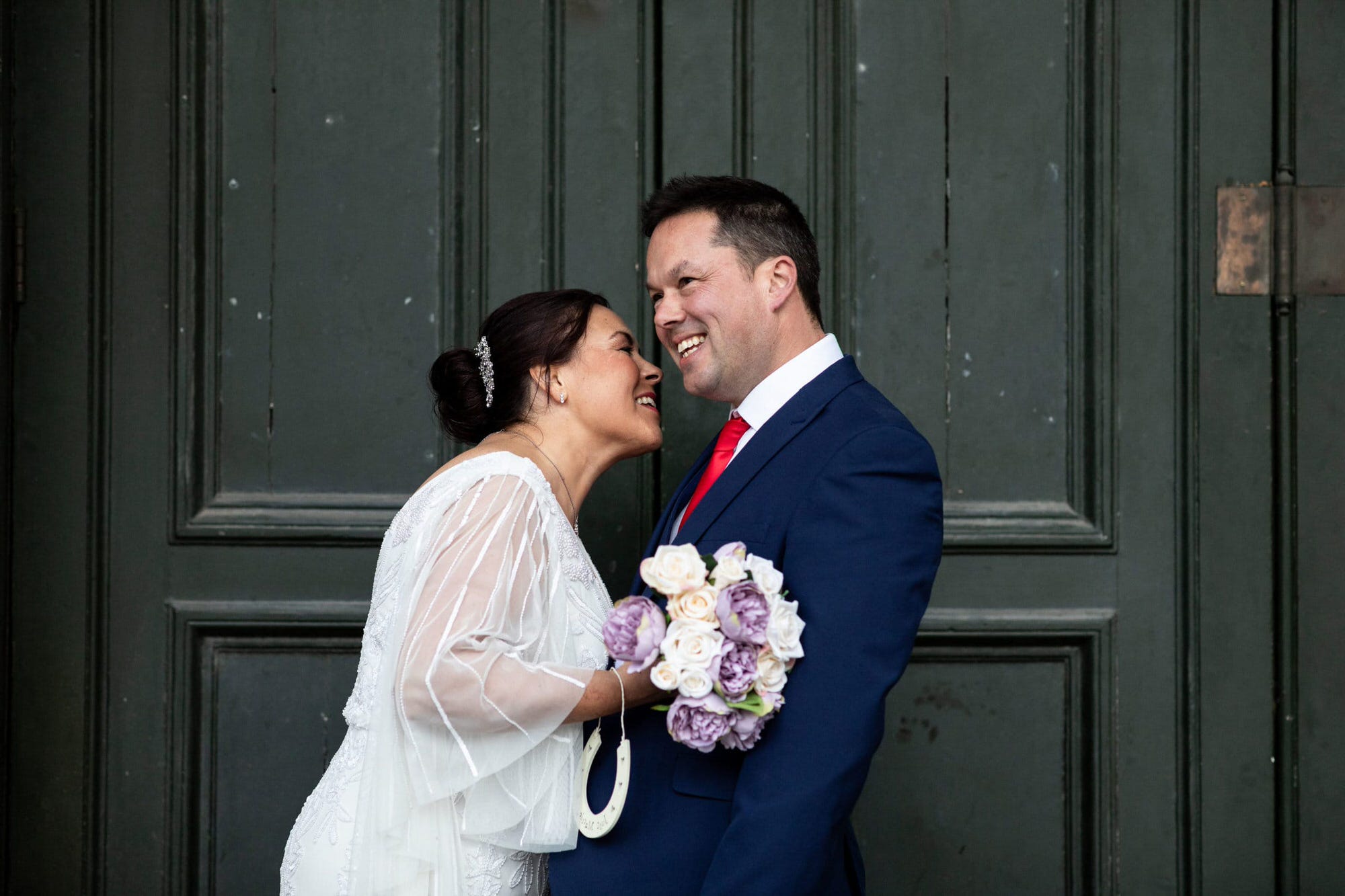 Groom and Bride in front of rustic green wooden door at their St Georges Hall Liverpool micro wedding by kent small wedding photographer
