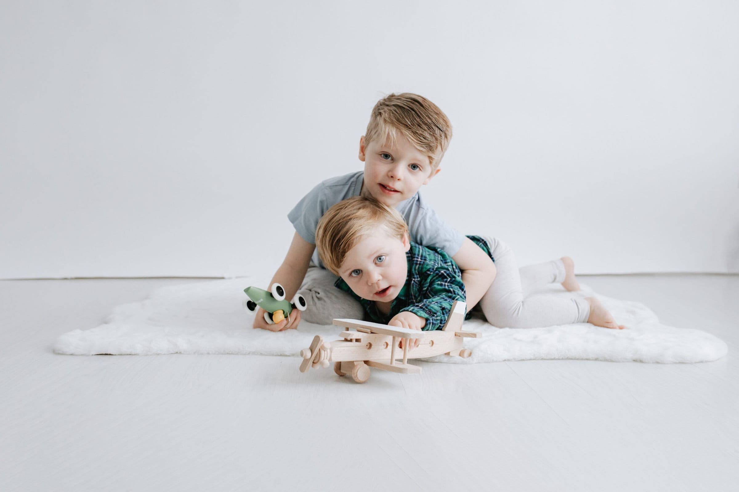 brothers laying on the floor playing with wooden toys at their kent family photoshoot in bexley