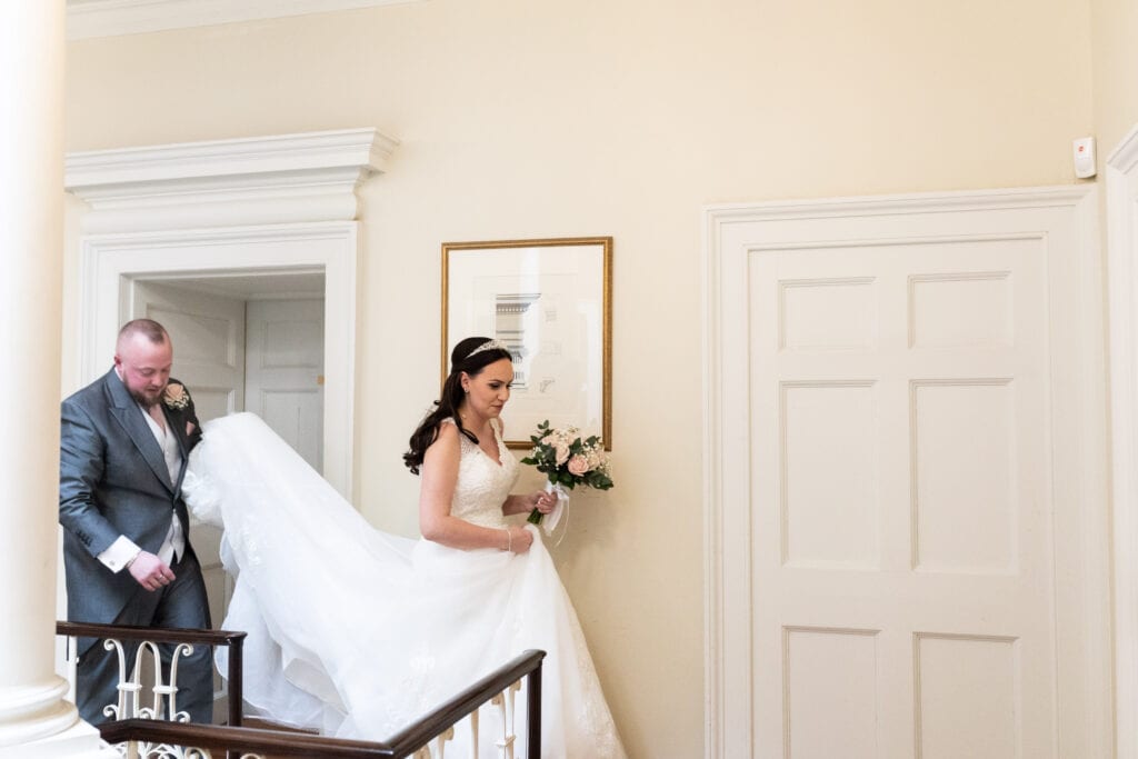 Bride with her train being held by her new husband walking along the gallery at Danson House Bexleyheath Micro wedding photography Kent