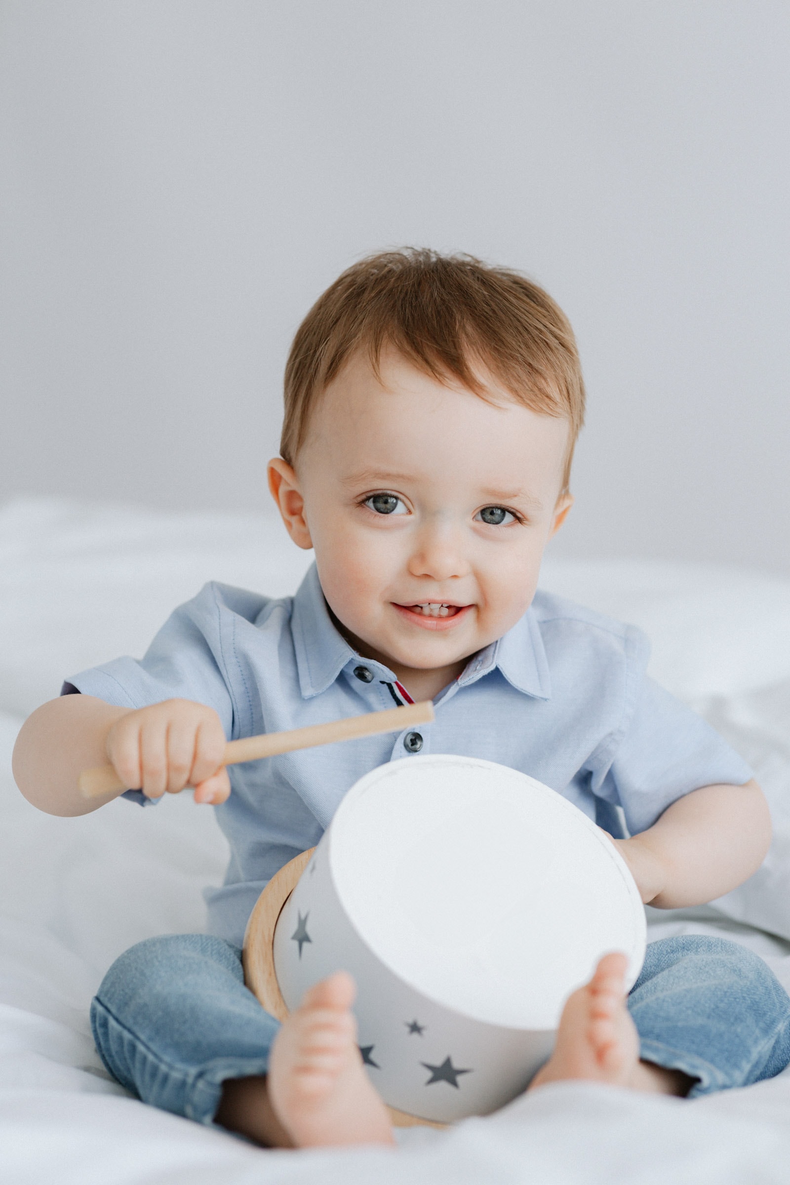 little boy playing with a wooden drum at his older baby studio photoshoot in bexley