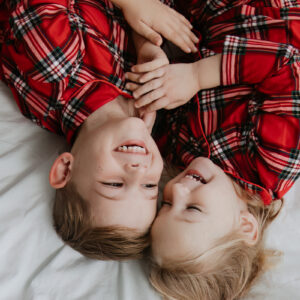 brother and sister in Christmas PJs laughing at their Bexley christmas photoshoot