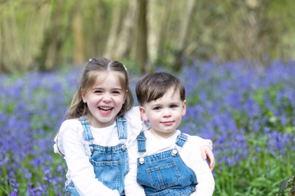 brother and sister laughing in the Kent bluebells at their Sevenoaks family photoshoot