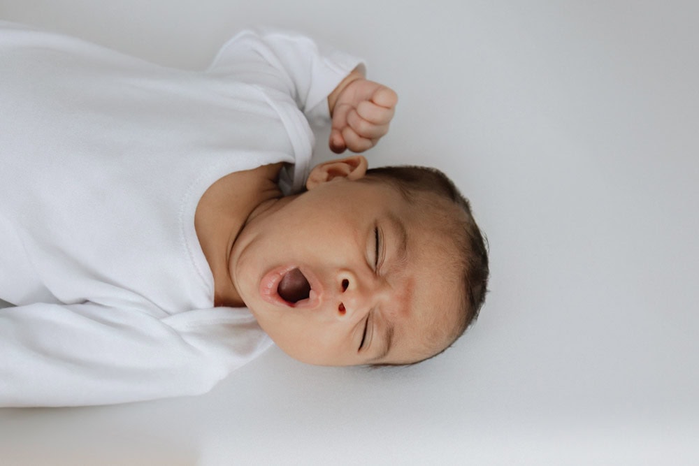 beautiful older newborn baby boy yawning at his bexley older newborn baby photoshoot in Kent